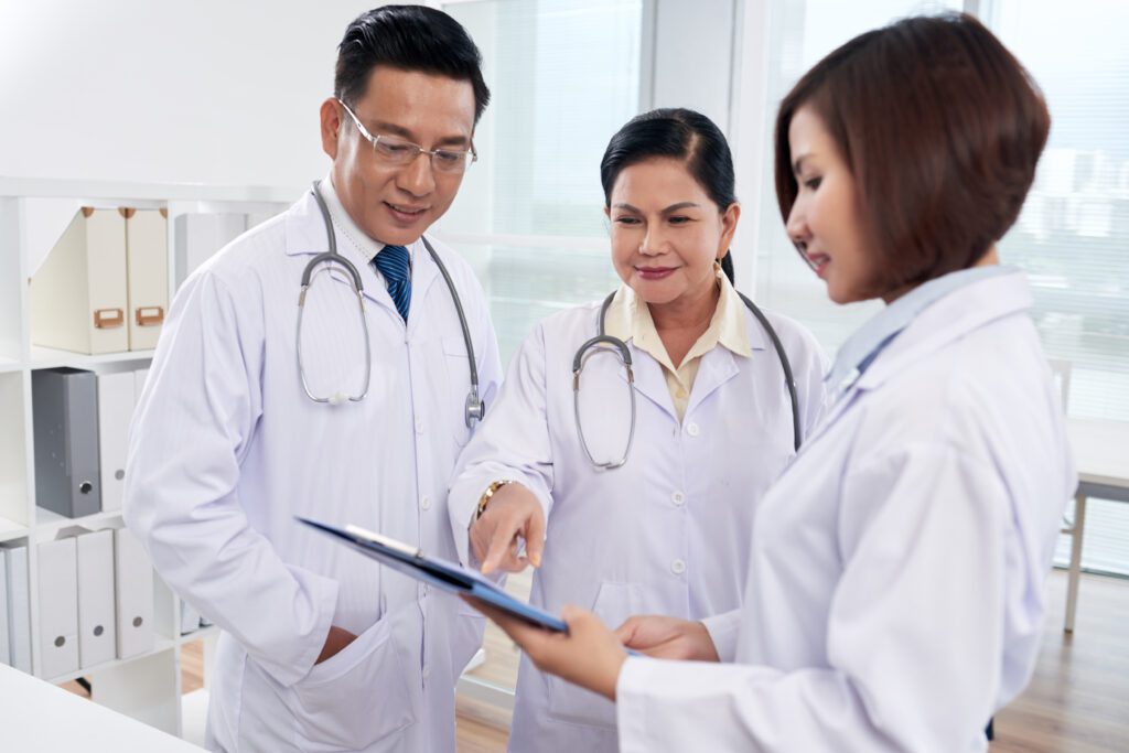 Three doctors are looking at a tablet.