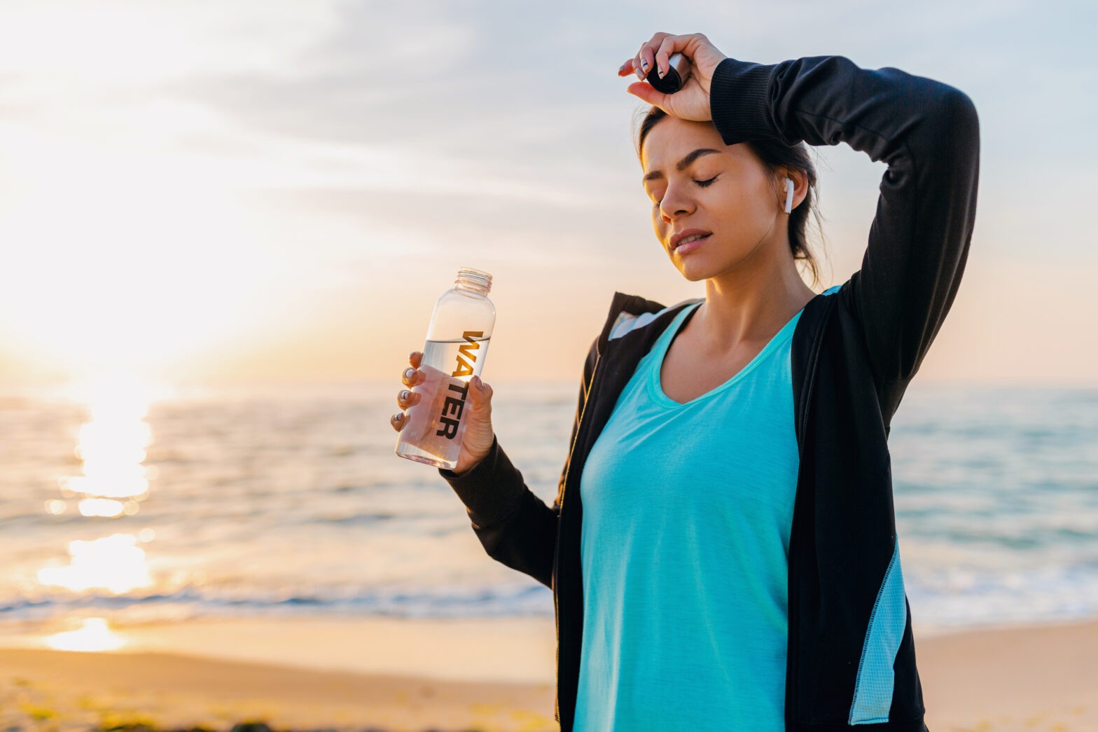 A woman holding onto a water bottle on the beach