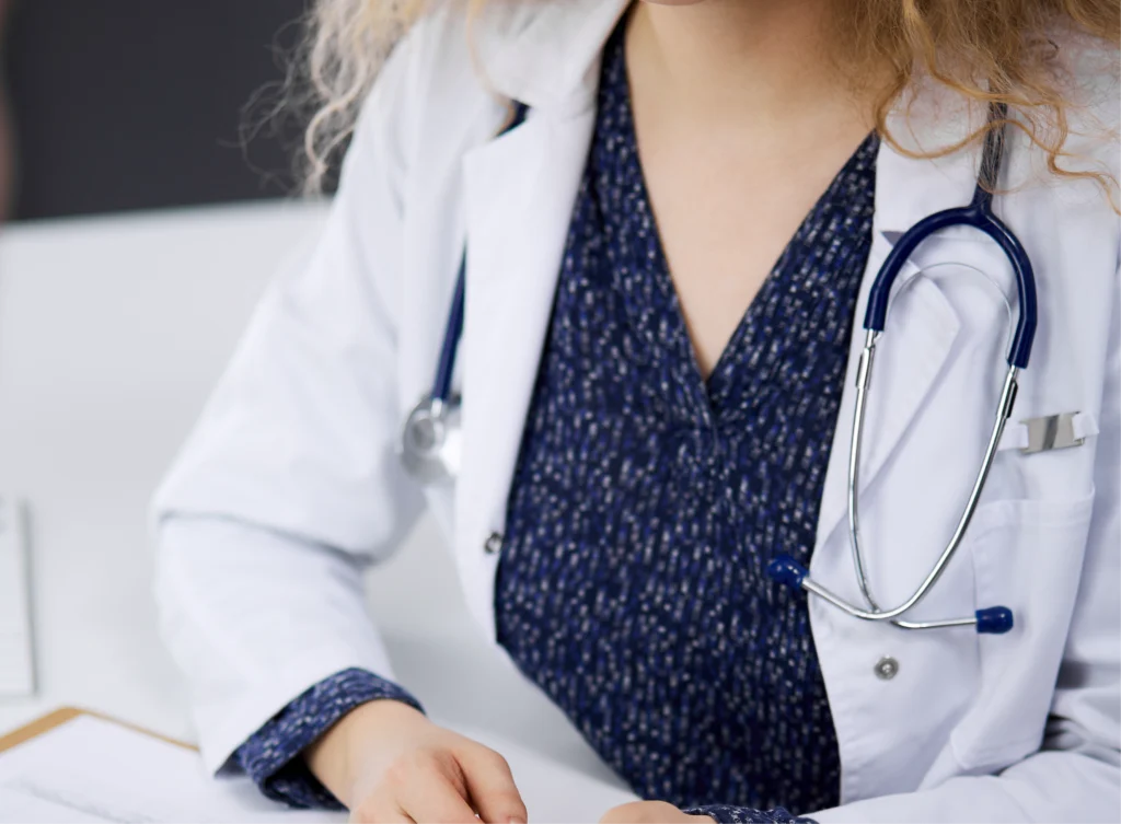 A woman in white lab coat and blue shirt.