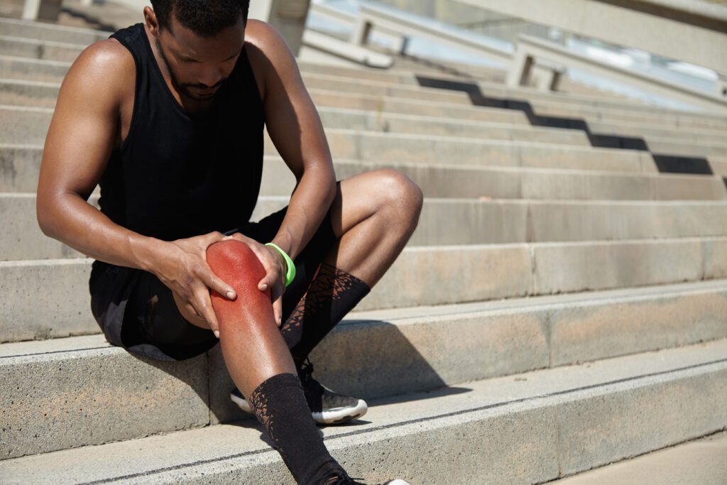 Man holding injured knee on stairs.