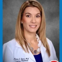 A woman in white lab coat and blue necklace.