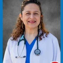A woman in white coat and blue shirt with stethoscope.