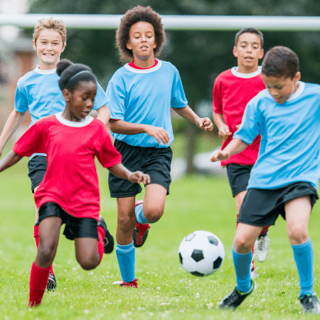 Kids playing soccer on the field.