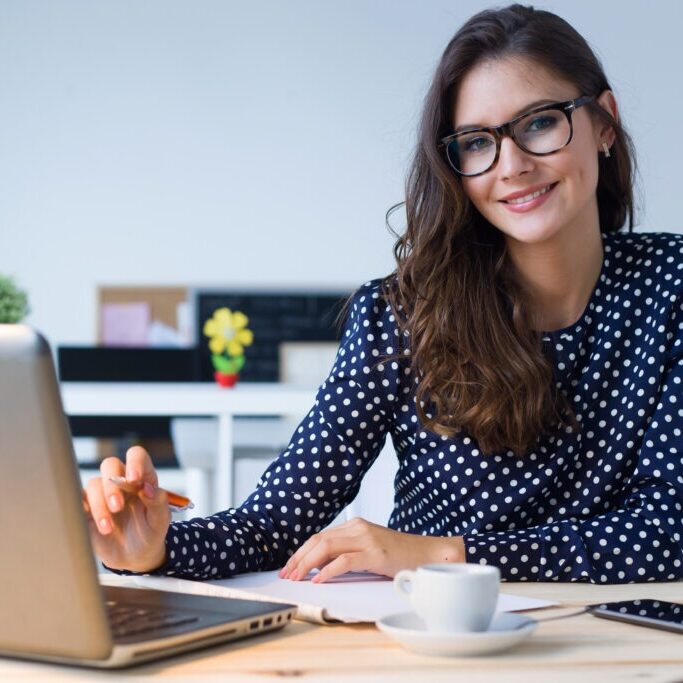 A woman sitting at a table with a laptop.