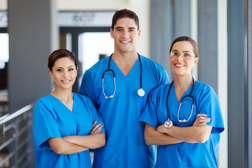 Healthcare professionals smiling in blue uniforms.