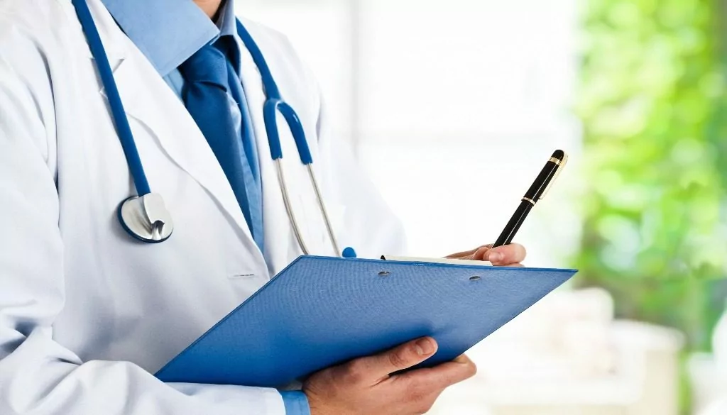 Doctor writing on clipboard with stethoscope.